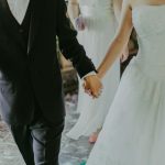Woman Wearing White Wedding Gown Holding Hands With Man While Walking