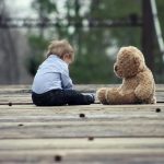 Boy Sitting With Brown Bear Plush Toy on Selective