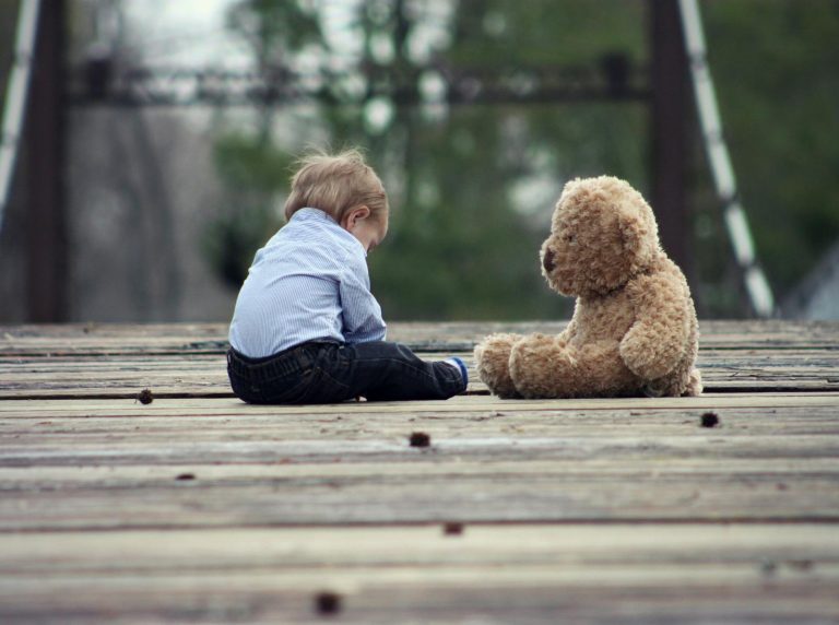 Boy Sitting With Brown Bear Plush Toy on Selective