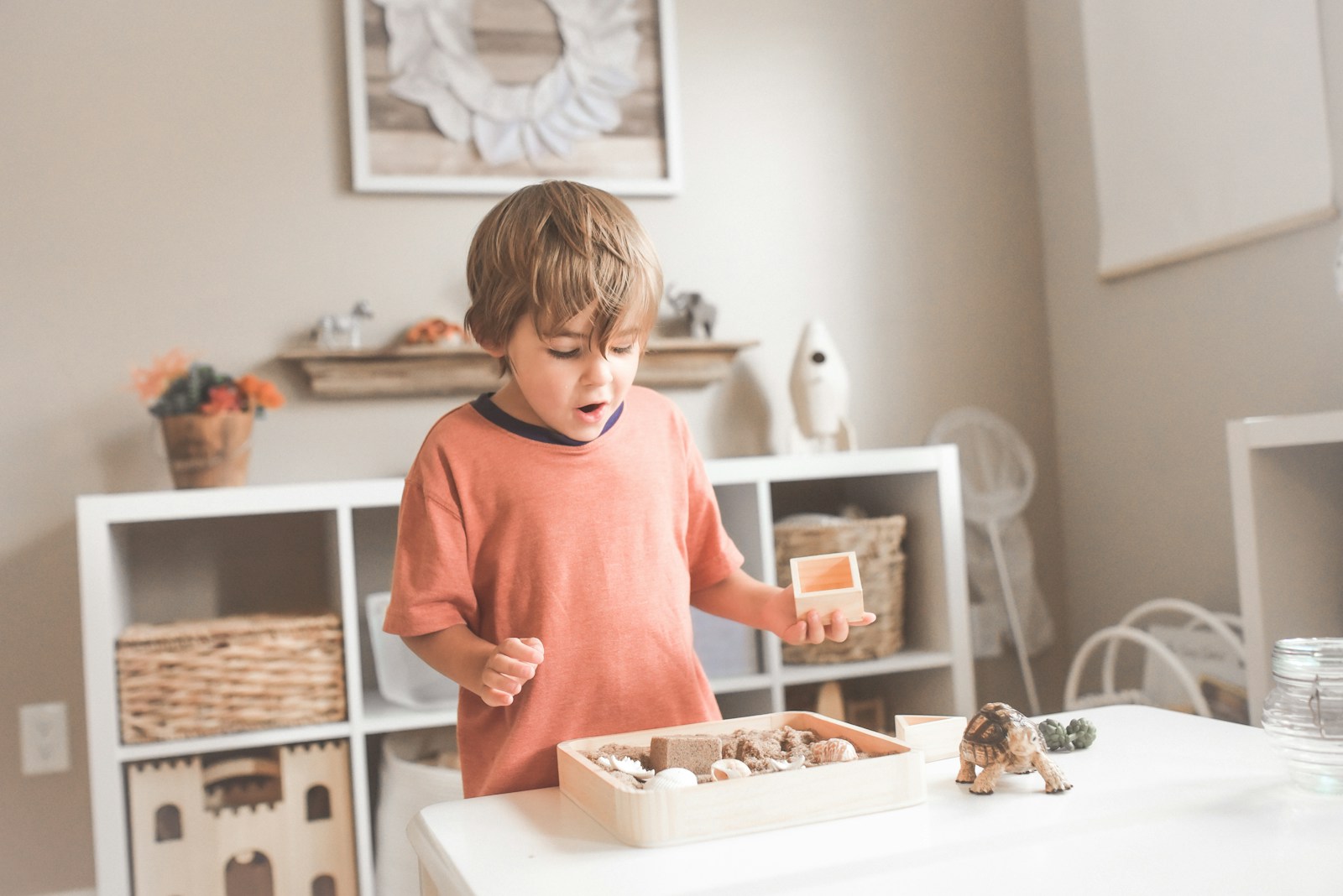 What Does Your Child's Play Behavior Tell You About Their Development? 1 boy in orange crew neck t-shirt standing in front of white wooden table with cupcakes