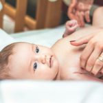 baby lying in white textile
