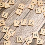 Scrabble letters spelling out sex on a wooden table