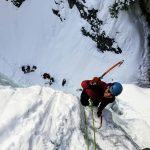 man wearing long-sleeved shirt climbing on mountain