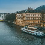 white and brown boat near river next to brown building during daytime