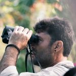man using black binoculars at daytime