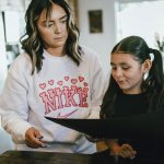 a woman standing next to a little girl in a kitchen