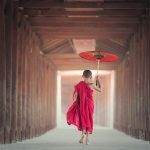 Boy Walking Between Wooden Frame While Holding Umbrella