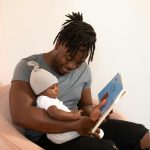 A Father Reading a Book to his Baby