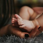 Person Holding Baby's Feet in Selective Focus Photography