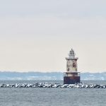 white and red lighthouse on the sea during daytime