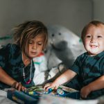 girl in blue and black crew neck t-shirt sitting beside white polar bear plush toy
