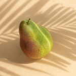 Fresh organic fruit pear located against white surface in sunbeam