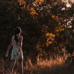 girl walking on brown grass near trees during daytime